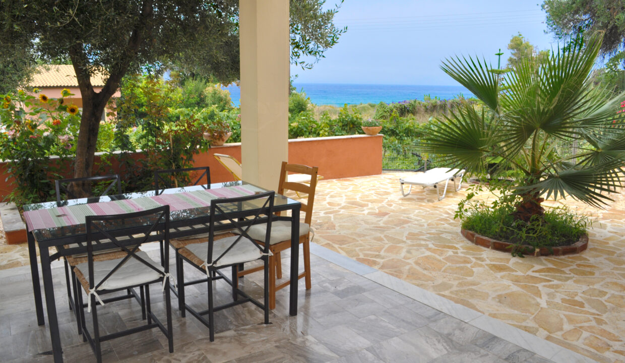Ferienhaus Angelos B -  großes überdachter Terrasse mit Gartenmöbeln und Blick auf das Meer.